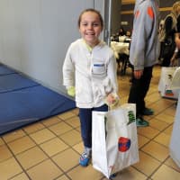 <p>Cate Ansel, 8, of Harrison helps carry packed bags outside for delivery.
</p>