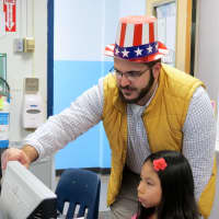 <p>Carrie E. Tompkins Elementary School technology manager Gregory Cavalieri helps a student with her letter.</p>