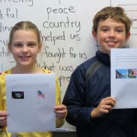 <p>Fourth-graders Caroline and Matthew show the letters they wrote to village veterans.</p>