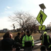 <p>Workers, city officials and media gather around a newly installed sign warning motorists of the crosswalk at Stillwater Avenue and Progress Drive. Mayor David Martin said the city is seeking to improve traffic safety in the city.</p>