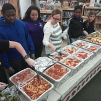 <p>Students and a PTA member prepare to serve food.</p>