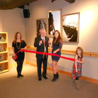 <p>First Selectman Michael Tetreau (center) is helped by owner Laura Laboissonniere (right) in the ceremonial ribbon cutting that took place inside the Pure Barre Studio, Friday, Dec. 5.</p>