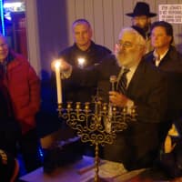 <p>Rabbi Yehoshua Hecht of Beth Israel of Westport/Norwalk lights candles on the menorah, assisted by Chief Thomas Kulhawik and Stew Leonard Jr.</p>