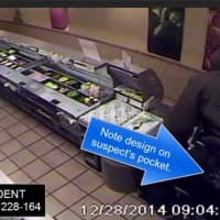 <p>In an image from a Stamford Police Department video, a suspect is seen jumping behind the counter of a Subway Restaurant in an attempted robbery on Sunday. The arrow points to a pattern on the suspect&#x27;s pants pocket. </p>