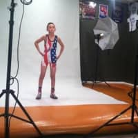 <p>Myles Griffin stands in front of cameras in front in his wrestling singlet.</p>