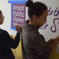 <p>Mount Vernon students Ella Stern (r) and Marsha Stern put finishing touches on wall mural at Amani Public Charter School, preparing for new facility opening.</p>