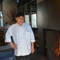 <p>Jorge Madrid, a chef at Zanni Restaurant, stands beside its fireplace.</p>