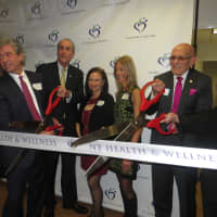 <p>Dr. Timothy Morley, medical director at NY Health &amp; Wellness, left, cuts the ribbon to his new center with Harrison Mayor Ron Belmont, right, as staff and other public officials look on Wednesday.</p>