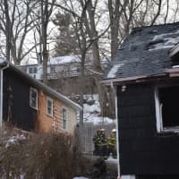 <p>A fire extensively damaged a Mahopac Falls home, right, also burned siding on a neighboring home, left. Firefighters can be seen in the center background.</p>