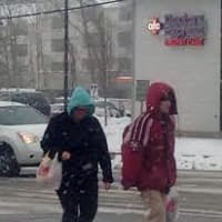 <p>Pedestrians carefully cross Main Street as snow begins to stick to the pavement. </p>