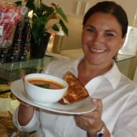 <p>Faina Yelensky, owner of Café Oo La La in Stamford holds up a hot soup and a hot sandwich while hot drink rests nearby.</p>