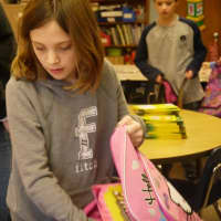 <p>A student stuffs a backpack with school supplies.</p>