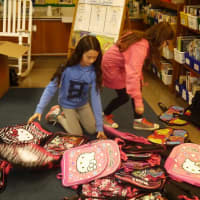 <p>Students prepare to stuff backpacks. </p>