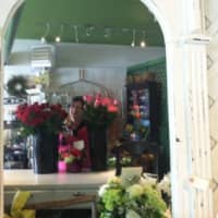 <p>Mary Jones, owner of Stewart Flowers &amp; Gifts at 76 Old Ridgefield Road, is seen here reflected in a mirror with an old store sign above.</p>