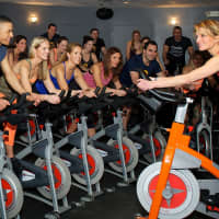 <p>Rhodie Lorenz leads an indoor cycling class at JoyRide in Darien.</p>
