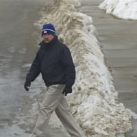 <p>A pedestrian crossing Main Street in Danbury also has to cross some big snowpiles. </p>