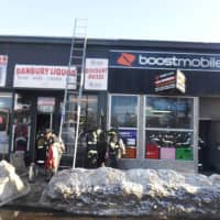 <p>Danbury firefighters douse a blaze at a Boost Mobile store at 20 White St. on Friday.</p>