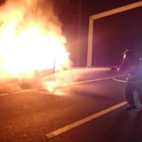 <p>A Westport firefighter attacks the burning car in the breakdown lane of I-95 on Sunday. </p>