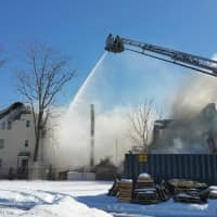 <p>All that remains of the center home is its chimney as Bridgeport firefighters work to put out a residential blaze. </p>
