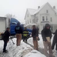 <p>A Danbury official talks with the residents as firefighters watch over the truck as it is pulled away from the house. </p>