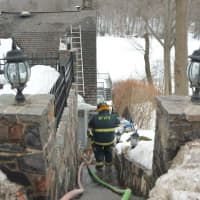 <p>Firefighters head towards a fire-damaged house that overlooks Lake Mahopac.</p>