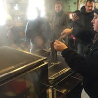 <p>Lisa Monachelli tests the concentration of the maple syrup in the Sugarhouse at the Stamford Museum and Nature Center.</p>