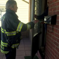 <p>Fire Inspector Kurt McDonald hands fire safety information to a resident following the fatal fire on Ely Avenue.</p>