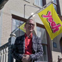 <p>Jon Campbell debuts his work, and here stands in front of one of his banners.</p>