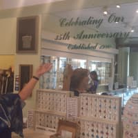 <p>Cynthia Valenti points to a new 35th anniversary sign inside her jewelry store at 1925 Palmer Ave.</p>