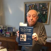 <p>Moshe Avital of New Rochelle with one of his Holocaust books.</p>