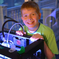 <p>Michael Walding, a seventh-grader at Seven Bridges Middle School, poses for photos beside a 3D printer.</p>