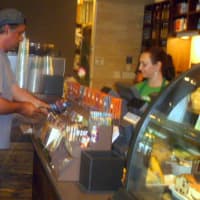 <p>A Wilton Starbucks customer pays for a cup of coffee Friday at the newly renovated shop.</p>