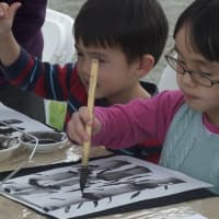 <p>Kids check out Sumie ink brush painting.</p>