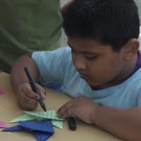 <p>A boy works on a piece in the Origami workshop.</p>