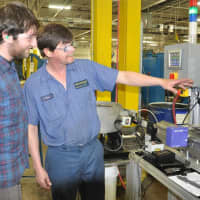 <p>Tony Curtis of Bristol, right, a trainer at Wallingfords Holo-Krome, explains the operation of the laser-measuring machine to intern and Housatonic Community College manufacturing student Nicholas Thommen of Fairfield. </p>