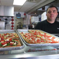 <p>Rudy mans the counter, and displays some of Wednesday&#x27;s specialty slices at Broadway Pizzeria.</p>