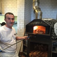 <p>Manager John Marleku next to the imported from Italy wood-fired oven.</p>