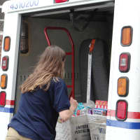 <p>A Wilton High School student volunteer unloads a postal truck in Norwalk.</p>