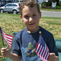 <p>A boy shows off a pair of flags Monday at the parade.</p>