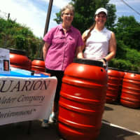 <p>Sharon England, left, owner of SkyJuice New England and Melissa Mickolyzck, of Aquarion, stand beside a water barrel. They are sold by SkyJuice in partnership with Aquarion.</p>