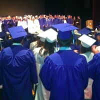 <p>Graduates and others sing the National Anthem at the Darien High School graduation ceremonies.</p>