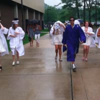 <p>Graduates brave the rain as they walk to Wilton High School on Saturday.</p>