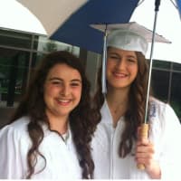 <p>Katherine Kahal, left, and Sarah Stroup stay dry before the Wilton High School graduation ceremonies.</p>