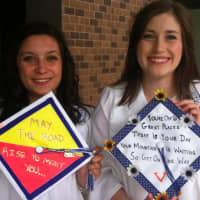 <p>Gabby Pucci, left, and Julia Davatzes hold up their decorated mortarboards.</p>