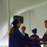 <p>A newly minted Horace Greeley graduate shakes hands with school board member Victoria Tipp.</p>