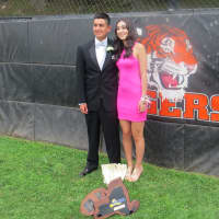 <p>Another happy prom couple poses for photos behind home plate. Championship plaques are in the foreground. </p>