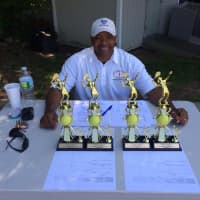 <p>Marvin Tyler of Slammer Tennis World sits at the scorer&#x27;s table with the tournament trophies.</p>