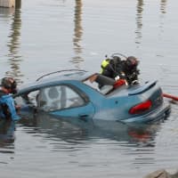 <p>Norwalk police divers Greg Scully and Bruce Lovallo secure a car that was driven into the inlet at Veterans Memorial Park in Norwalk Saturday.</p>