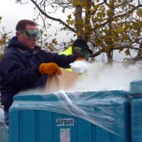 <p>A Con Edison worker scoops dry ice into a bag to distribute to customers without power Wednesday at Empire City Casino.</p>