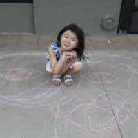 <p>Suni, of Scarsdale, shows off her sidewalk chalk art at the Cross County Shopping Center.</p>